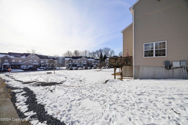 yard layered in snow with a residential view and a wooden deck