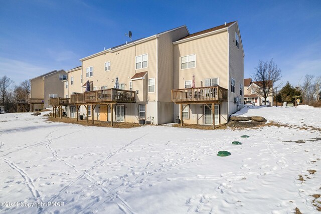 snow covered rear of property with a wooden deck