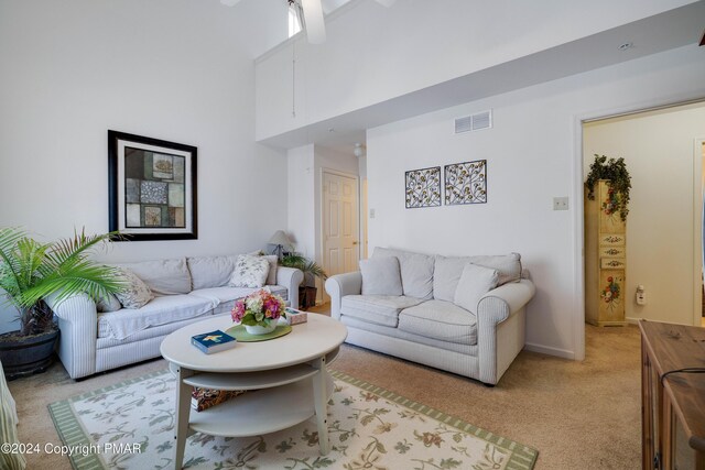 living area featuring a towering ceiling, baseboards, visible vents, and light colored carpet