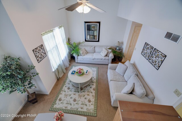 carpeted living area featuring ceiling fan, a towering ceiling, visible vents, and baseboards