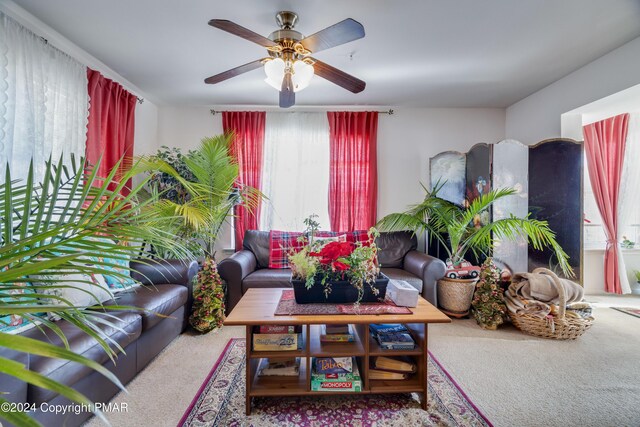 carpeted living area with a ceiling fan