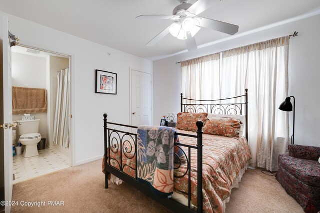 carpeted bedroom with a ceiling fan, connected bathroom, visible vents, and baseboards