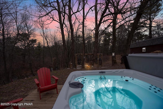 pool at dusk featuring a hot tub