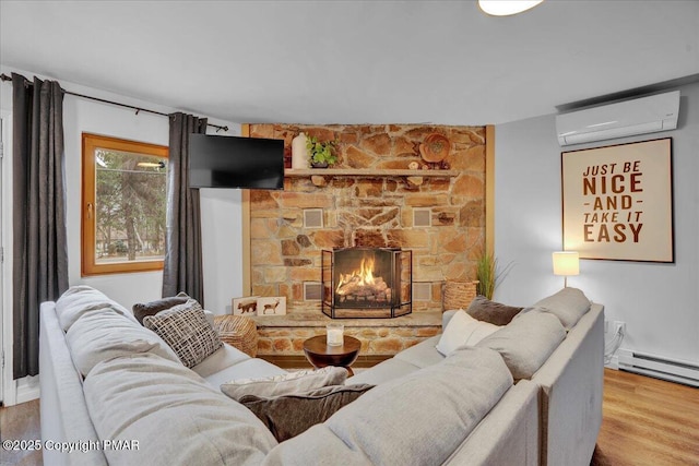 living room featuring baseboard heating, wood-type flooring, a fireplace, and an AC wall unit