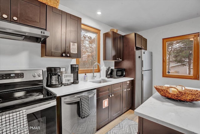 kitchen featuring a sink, appliances with stainless steel finishes, ventilation hood, and light countertops