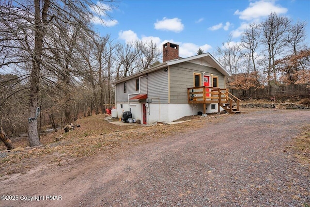 view of property exterior featuring dirt driveway, central AC, and a chimney