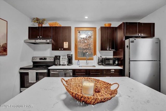 kitchen with under cabinet range hood, stainless steel appliances, light stone counters, and a sink