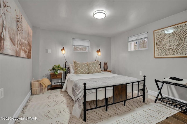 bedroom with multiple windows, light hardwood / wood-style flooring, and baseboard heating