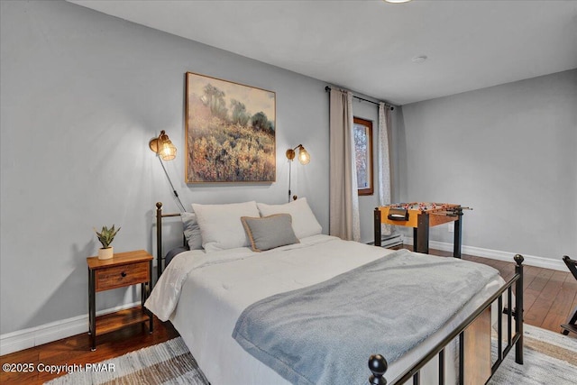 bedroom with baseboard heating, baseboards, and wood finished floors