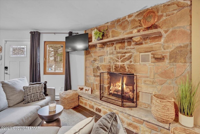 living area featuring visible vents, a fireplace, and wood finished floors