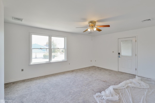 carpeted empty room with ceiling fan, visible vents, and baseboards