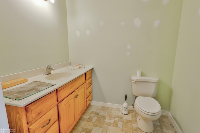 bathroom with baseboards, vanity, and toilet