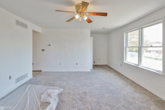 spare room with light colored carpet, ceiling fan, and visible vents