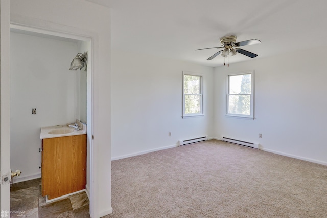 unfurnished bedroom featuring a sink, baseboards, baseboard heating, and carpet flooring