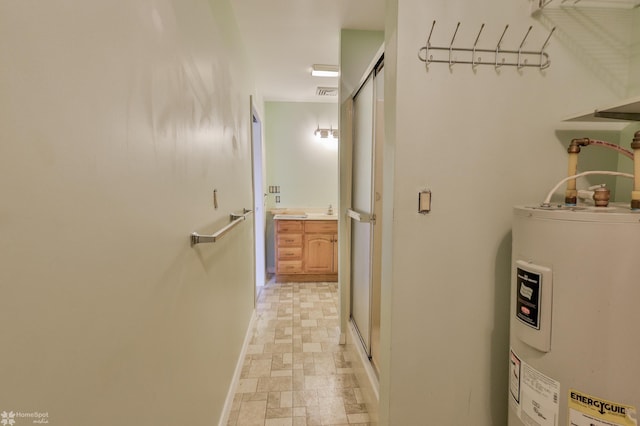 hall featuring baseboards, visible vents, stone finish floor, and electric water heater