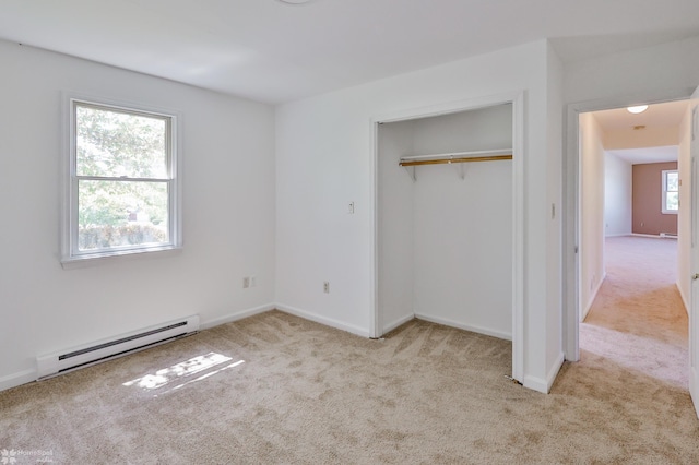 unfurnished bedroom with a closet, baseboards, a baseboard heating unit, and carpet flooring