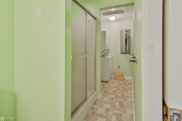 bathroom featuring an enclosed shower, baseboards, stacked washing maching and dryer, and electric panel