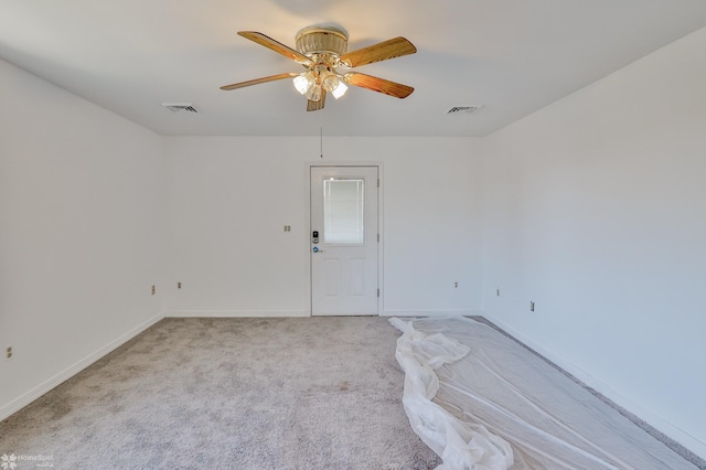 empty room with visible vents, a ceiling fan, baseboards, and light carpet