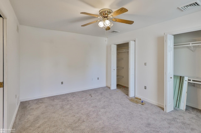 unfurnished bedroom featuring multiple closets, carpet floors, and visible vents