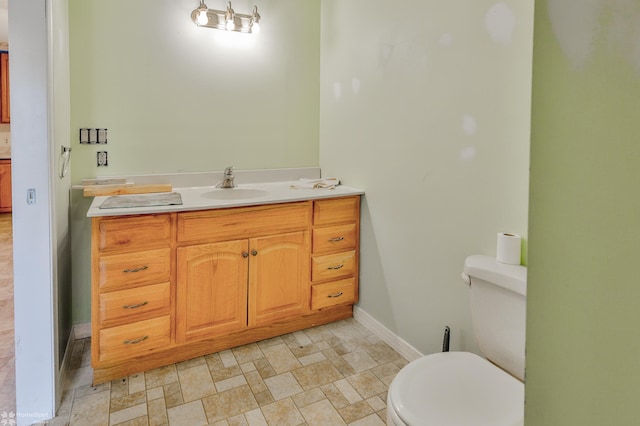 bathroom featuring toilet, baseboards, and vanity
