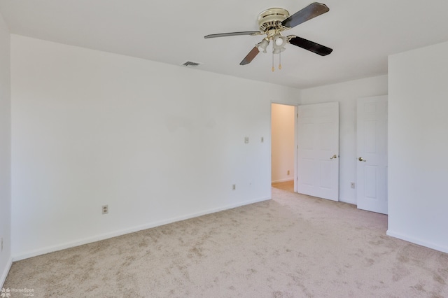 carpeted empty room featuring baseboards, ceiling fan, and visible vents
