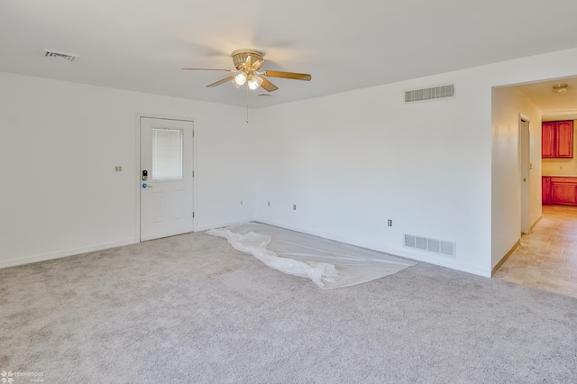 unfurnished room featuring baseboards, ceiling fan, light colored carpet, and visible vents