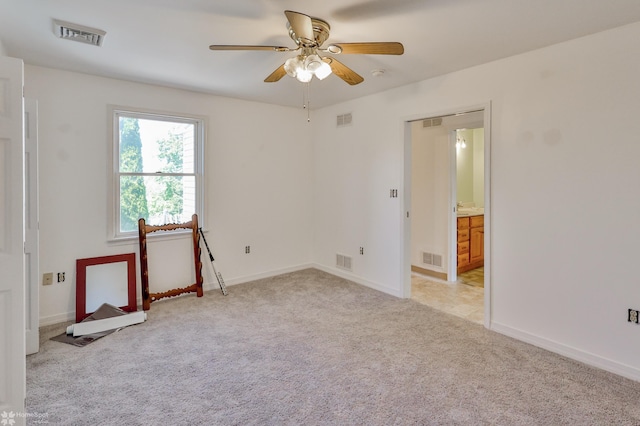 empty room featuring visible vents, a ceiling fan, and light carpet