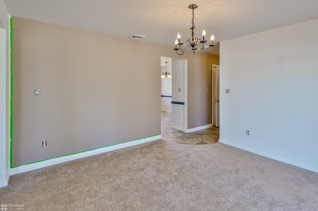 carpeted spare room featuring visible vents, baseboards, and a notable chandelier