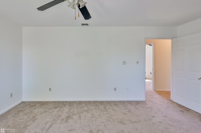 empty room with baseboards, a ceiling fan, carpet flooring, and visible vents