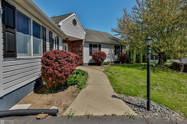 exterior space with roof with shingles and a yard