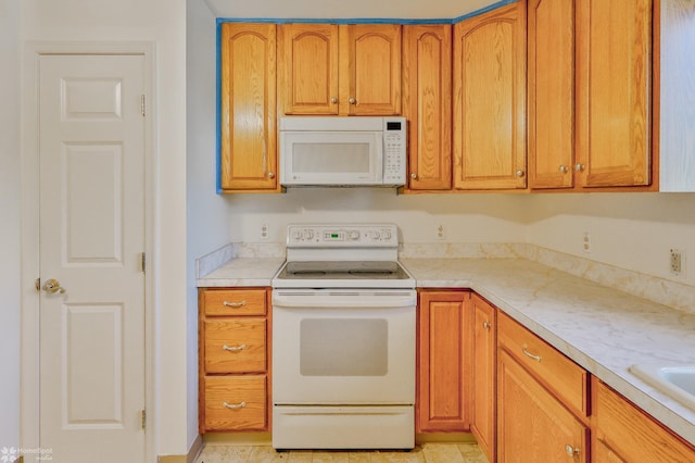 kitchen with white appliances, brown cabinetry, and light countertops