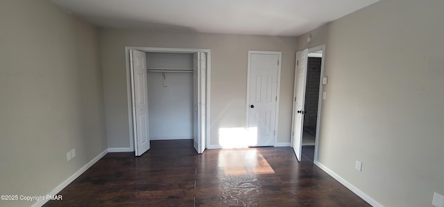 unfurnished bedroom with baseboards, dark wood-style flooring, and a closet