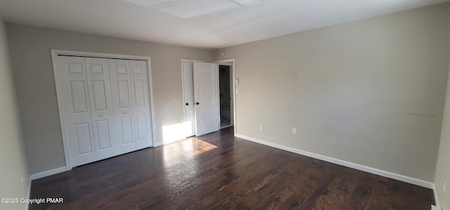 unfurnished bedroom with dark wood-type flooring, baseboards, and a closet