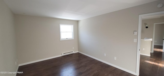 spare room with a baseboard heating unit, dark wood finished floors, and baseboards