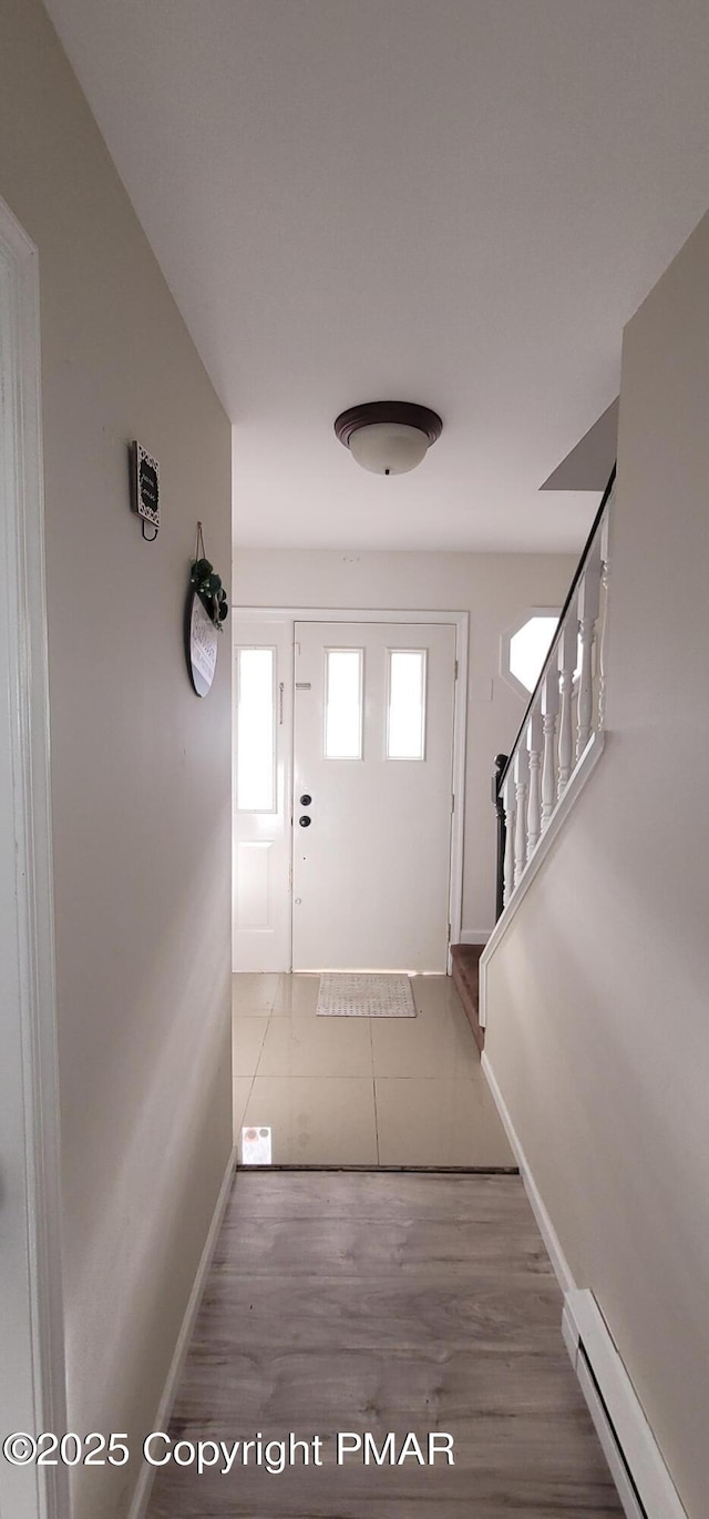 foyer featuring stairway, wood finished floors, baseboards, and a baseboard radiator