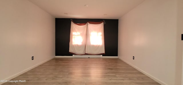 unfurnished room featuring light wood finished floors, baseboards, and baseboard heating