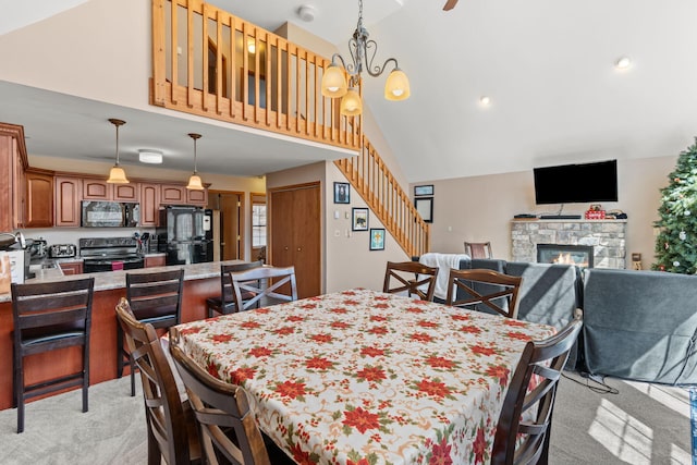 dining space featuring high vaulted ceiling, stairway, light colored carpet, and a fireplace