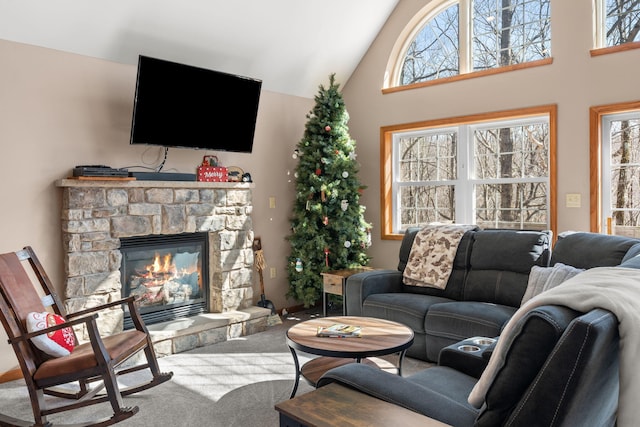 living area with a fireplace, carpet flooring, a healthy amount of sunlight, and high vaulted ceiling