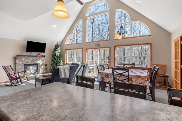 carpeted dining room with plenty of natural light, a fireplace, and high vaulted ceiling