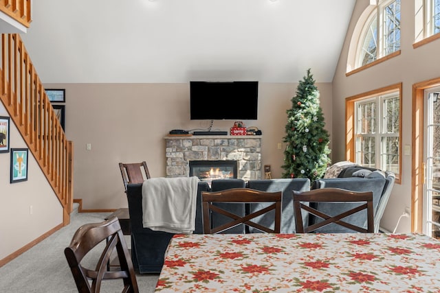 carpeted living room with stairs, a fireplace, baseboards, and high vaulted ceiling