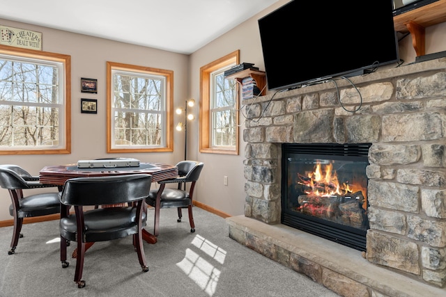 carpeted dining area with baseboards and a stone fireplace