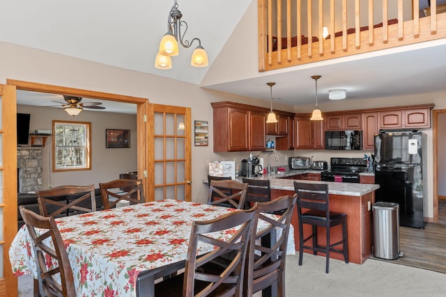 kitchen featuring a breakfast bar area, pendant lighting, black appliances, and ceiling fan