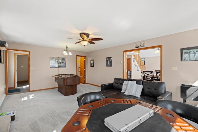 carpeted living area featuring ceiling fan with notable chandelier and baseboards