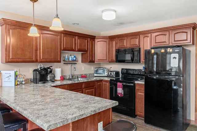 kitchen with a breakfast bar, a peninsula, a sink, black appliances, and light countertops