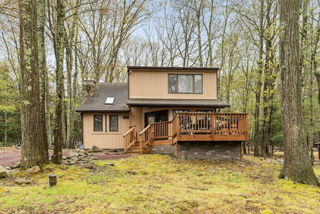 view of front of property with a shingled roof, a chimney, and a wooden deck