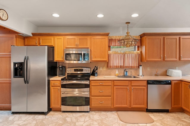 kitchen featuring a sink, pendant lighting, an inviting chandelier, light countertops, and appliances with stainless steel finishes