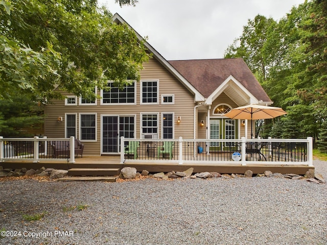 back of house with a shingled roof and a deck