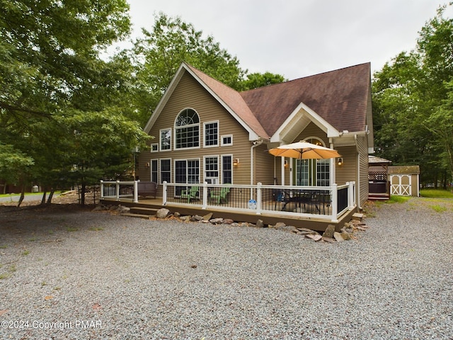 chalet / cabin with a deck, an outbuilding, and roof with shingles