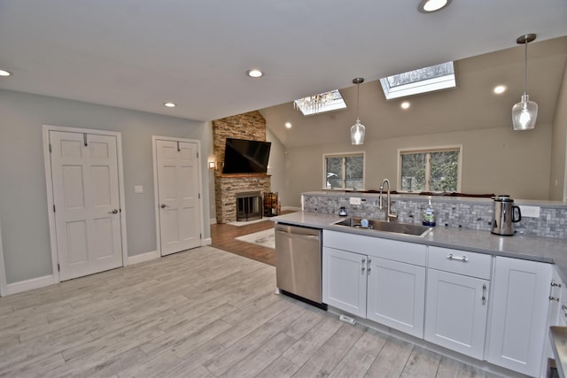 386 Camelback Rd, Tannersville, PA 18372 - kitchen featuring stainless steel dishwasher, a fireplace, white cabinetry, a sink, and hanging light fixtures