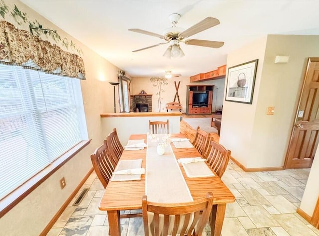 3708 Bayberry Dr, Danielsville, PA 18038 - dining area with light stone finish floors, a ceiling fan, and a fireplace